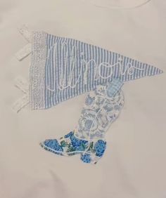 a white shirt with blue and white designs on the front, along with an embroidered boot