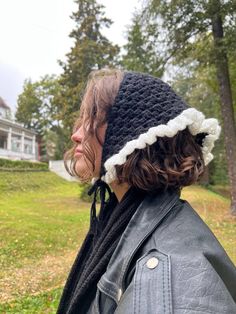 a woman wearing a black and white crochet beanie hat with ear flaps