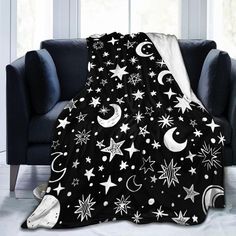 a black and white blanket with stars, moon and crescents on it in front of a couch