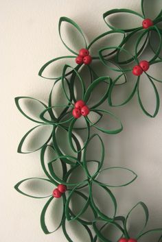 a wreath made out of green paper with red buttons and leaves on the front side