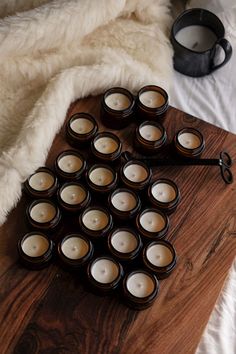 tealight candles are arranged on a wooden tray next to a white fur covered bed