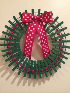 a wreath made out of popsicle sticks with a red bow on the top and green stems