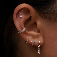 a woman wearing three different types of ear piercings on her left ear and the other one has a diamond set in it