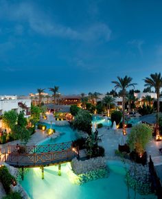 an aerial view of a resort at night with lights on the pool and palm trees in the background