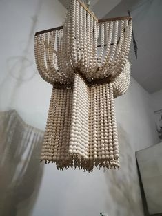 a chandelier made out of beads hanging from the ceiling in a room with white walls