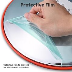 a hand holding a piece of clear plastic on top of a round mirror with the words protective film over it