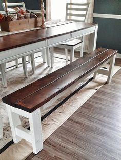 a wooden bench sitting on top of a hard wood floor next to a white table