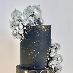 a black and gold cake with disco balls on it's top, decorated with the number 50