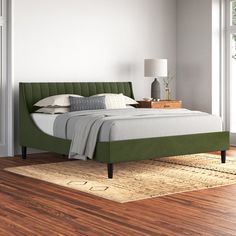 a bed with green headboard and foot board in a white room next to a window