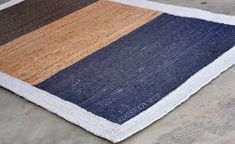 a blue, brown and white rug sitting on top of a cement floor next to a wall