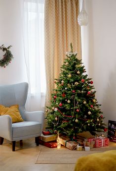 a living room with a christmas tree in the corner and presents on the floor next to it