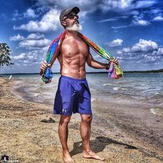 an older man standing on the beach with his scarf around his neck