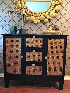 a black and gold dresser with a mirror above it on the wall next to a red tile floor