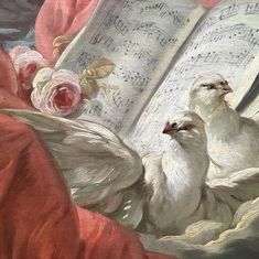 two white doves are sitting next to an open book with music notes on it