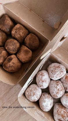 two boxes filled with donuts sitting on top of a wooden table next to each other