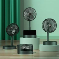 three metal fans sitting on top of each other in front of a green curtained window