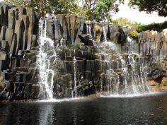 a large waterfall in the middle of a body of water with rocks on both sides