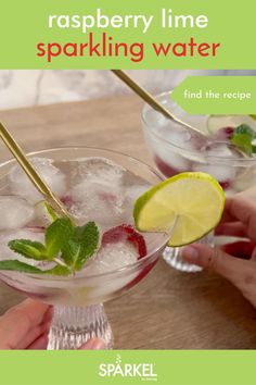 two glasses filled with ice and strawberries on top of a wooden table next to limes