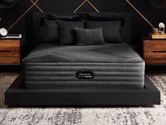 a black bed with two pillows on top of it next to a night stand and nightstands