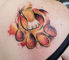 the back of a woman's shoulder with an orange and yellow tattoo design