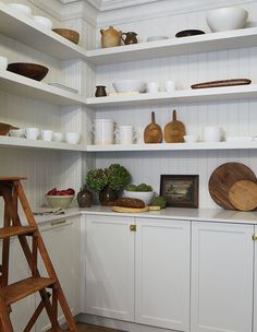 the shelves in this kitchen are filled with bowls and other things to cook for dinner