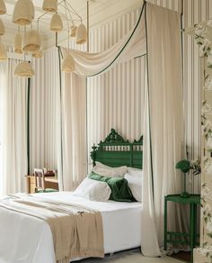 a bed with white sheets and green headboard in a room that has curtains on the walls