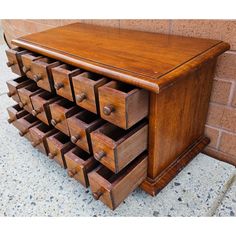 an old wooden drawer with many drawers on the top and bottom, next to a brick wall