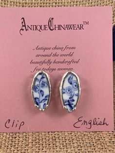 pair of blue and white porcelain earrings with floral designs on the backs, in front of a pink card