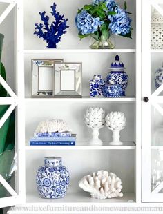 blue and white vases are sitting on the shelves in this china cabinet, along with other decorative items