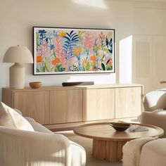 a living room filled with furniture and a painting hanging on the wall over a coffee table