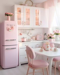 a pink refrigerator in a kitchen next to a table with chairs and flowers on it