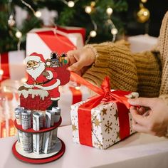 a person is wrapping presents in front of a christmas tree