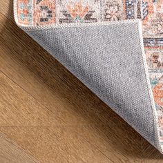 an orange and blue area rug on top of a wooden floor next to a wood floor