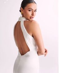 a woman in a white dress with her back turned to the camera and wearing gold earrings