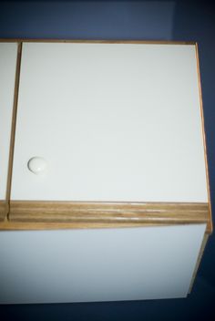 a white refrigerator with a wooden door and knob on the top shelf in a kitchen