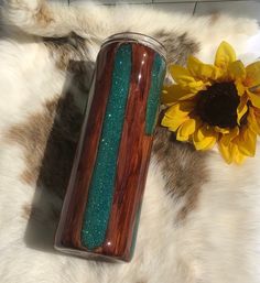 a vase sitting on top of a fur covered floor next to a sunflower and a yellow flower