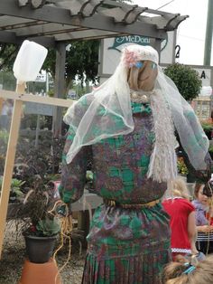 a woman in a green dress and veil standing next to a potted planter