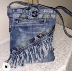 an old pair of jeans has been ripped and is sitting on a table with a handbag in it