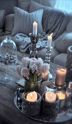 a table topped with candles and flowers on top of a wooden table next to a couch