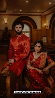 a man and woman sitting next to each other in formal wear, posing for the camera