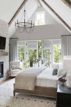 a bedroom with a large bed sitting under a chandelier next to a fireplace