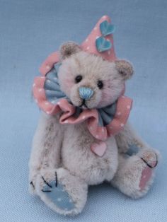 a small teddy bear with a bow on it's head sitting against a blue background