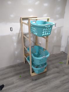 two blue baskets sitting on top of a wooden shelf next to a white wall in a room