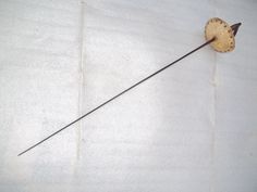 an old fashioned clock on a white wall with a long stick sticking out of it