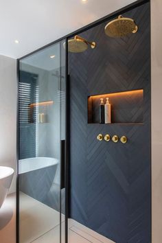 a bathroom with a glass shower door and gold fixtures on the wall, along with a white bathtub