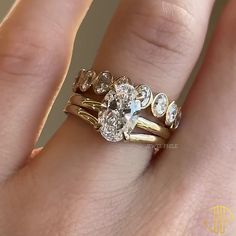 a woman's hand with three gold rings on it and an engagement ring in the middle