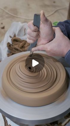 a person making a vase out of clay on a wheel with a knife in their hand