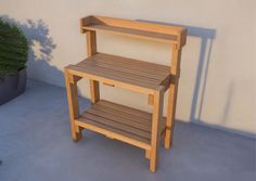 a wooden shelf sitting next to a potted plant