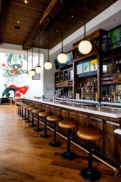 an empty bar with stools and lights hanging from the ceiling in front of it