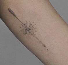 a small tattoo on the arm of a woman with an arrow and starburst